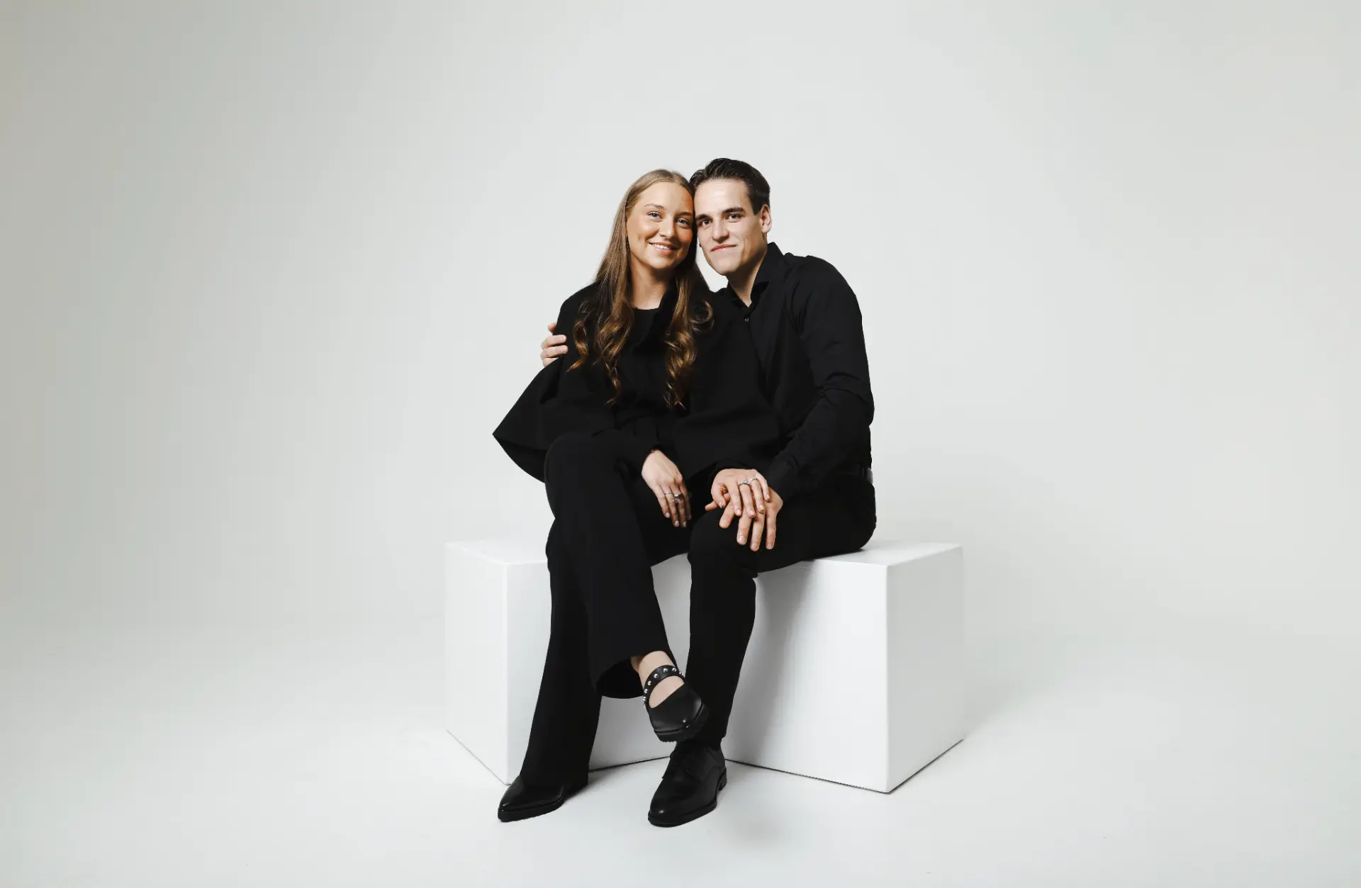 Portrett av par i svart tøy fotografert i studio mot lys bakgrunn